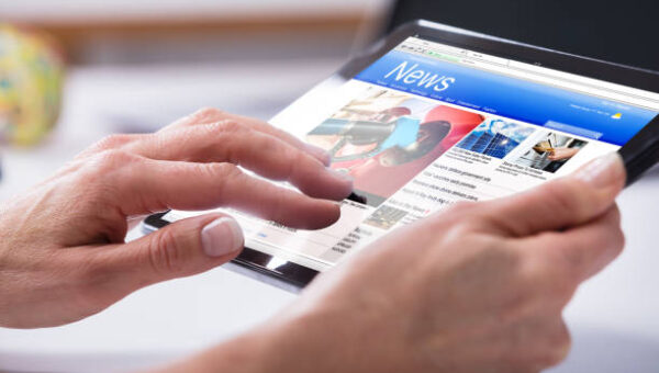 Close-up Of A Person's Hand Using Digital Tablet With Screen Showing Online News